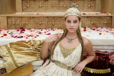 Barbara Palvin as Antimache in Hercules (2014), wearing a headdress and ancient Greek outfit, surrounded by petals on a golden background.