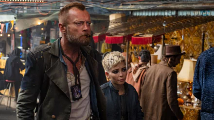 HD desktop wallpaper from The Watch featuring two characters in a bustling market scene.