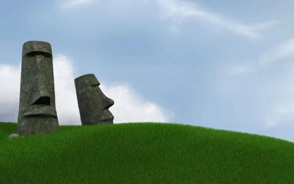 HD desktop wallpaper featuring two man-made moai statues with distinct faces against a clear sky and green grassy hill.