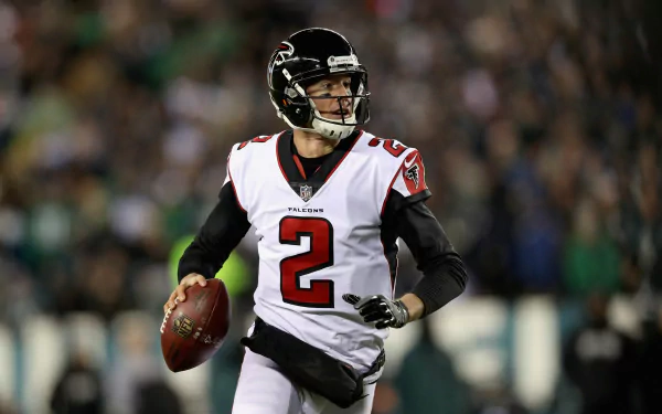 HD wallpaper featuring Matt Ryan, wearing his Atlanta Falcons uniform, in action on the football field, showcasing his dynamic athleticism and determination.