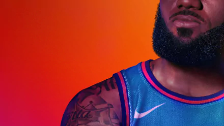 Cropped close-up of a bearded basketball player’s shoulder and blue jersey with tattoos against an orange gradient — Space Jam 2 movie 8K Ultra HD PC desktop wallpaper.