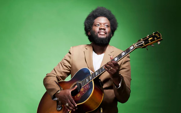 A man with a guitar posing for an HD desktop wallpaper on a green background.