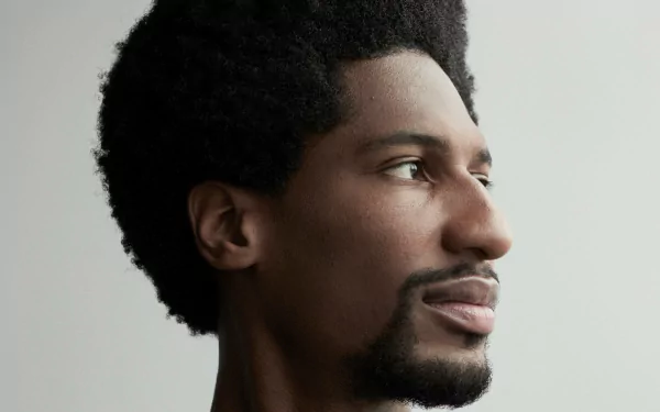 HD desktop wallpaper featuring a side portrait of a man with an afro against a neutral background.