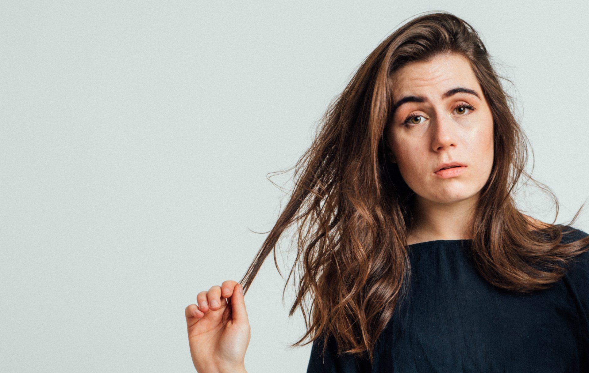 A high-definition desktop wallpaper featuring Dodie, showcasing her thoughtful expression and long, wavy hair against a light background, capturing the essence of her music.