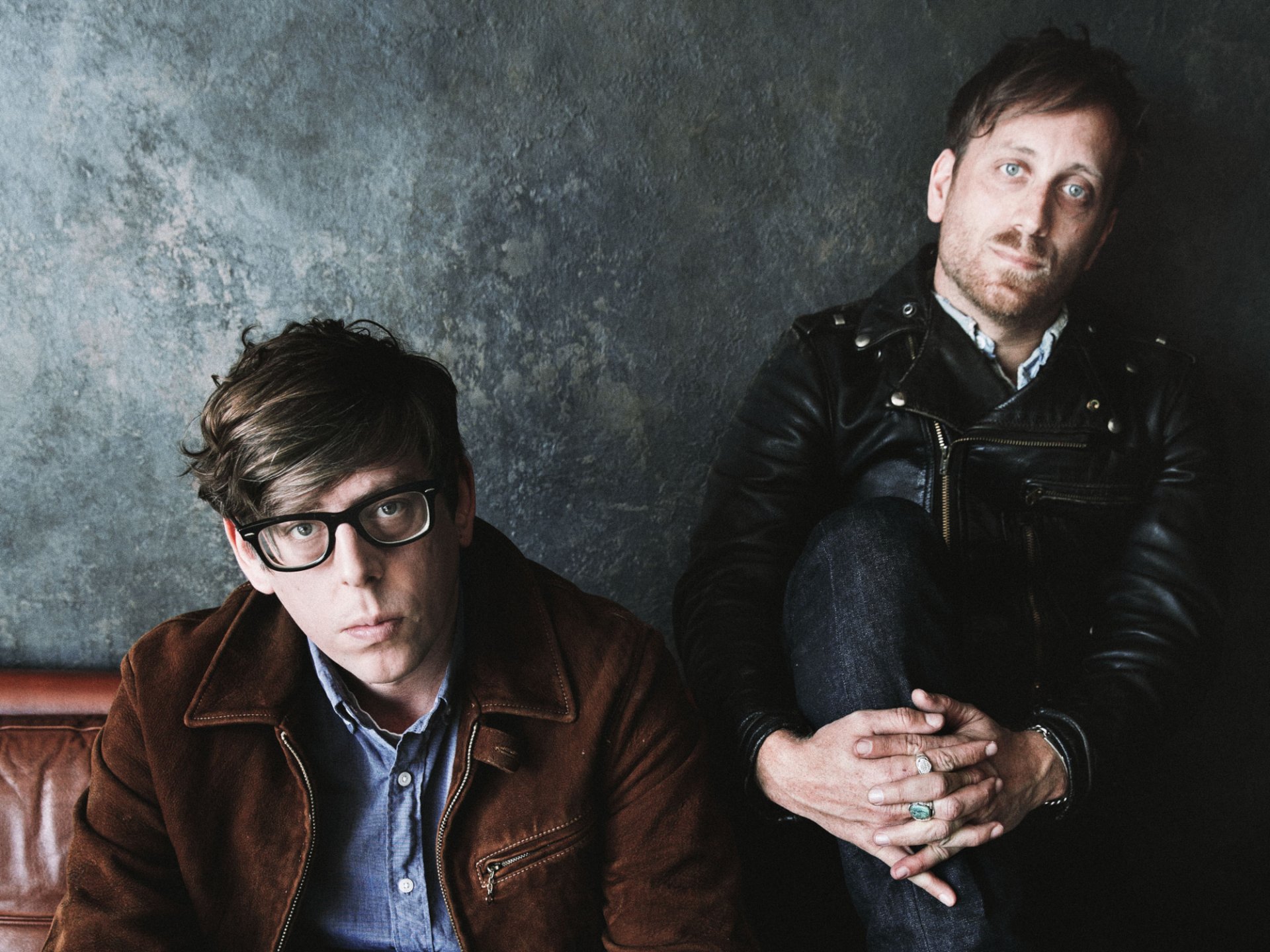 HD desktop wallpaper featuring two band members sitting against a textured backdrop, representing The Black Keys style.