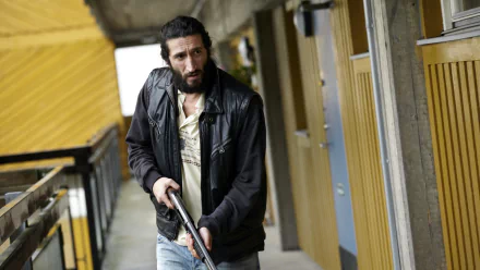 HD desktop wallpaper from Snabba Cash featuring a man with a gun in a tense hallway scene.