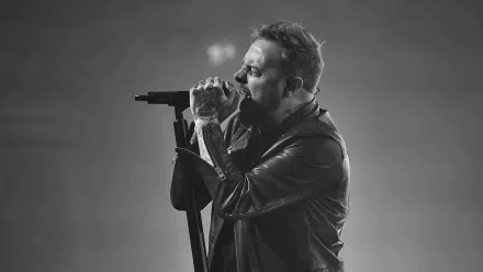 HD wallpaper of a person singing into a microphone with a moody, monochrome backdrop, tagged as Architects.