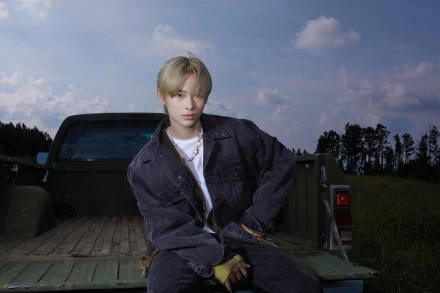 4K Ultra HD desktop wallpaper featuring ENHYPEN member posing on the back of a truck under a partly cloudy sky, blending music and scenic outdoor elements.