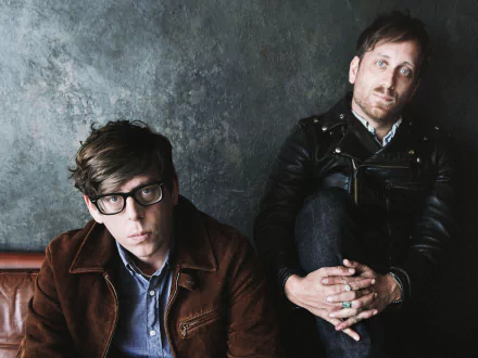 HD desktop wallpaper featuring two band members sitting against a textured backdrop, representing The Black Keys style.