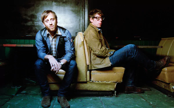 HD wallpaper featuring two band members sitting back-to-back in vintage interior, evoking The Black Keys' style.