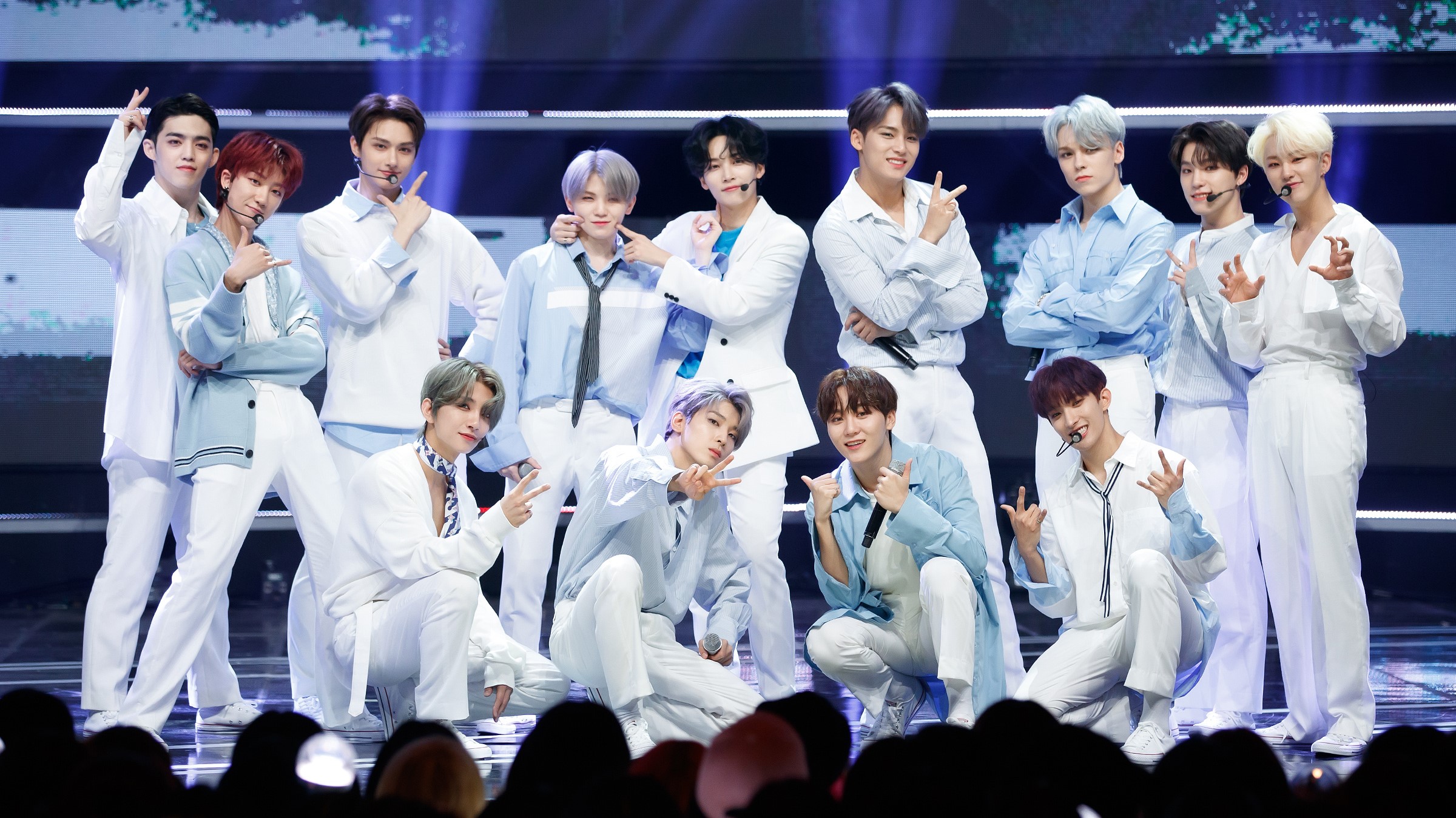 HD desktop wallpaper featuring the K-pop group Seventeen in coordinating white outfits, posing on stage for a lively performance, perfect for a vibrant desktop background.