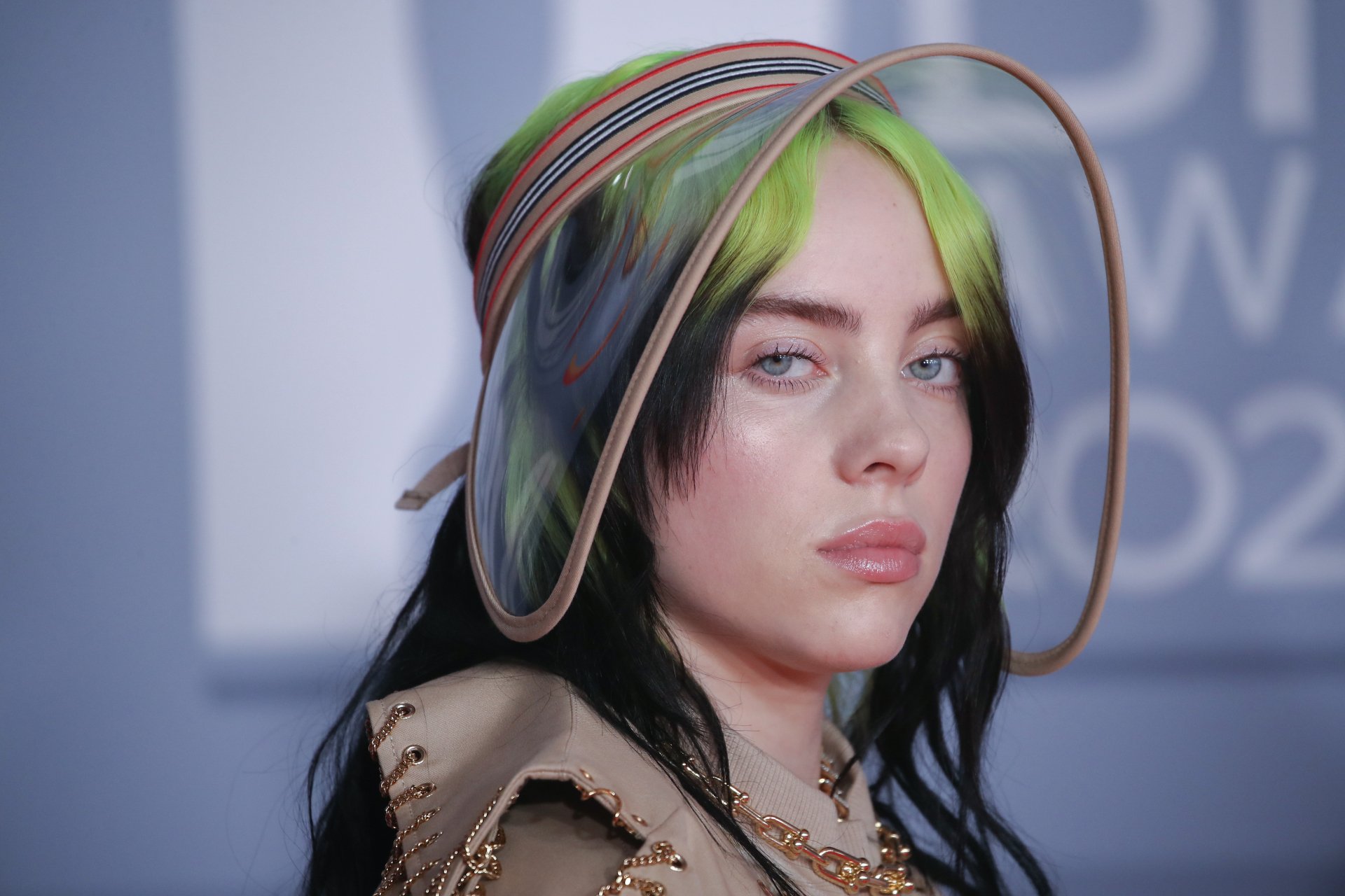 4K Ultra HD PC desktop wallpaper of American singer Billie Eilish with green and black hair, wearing a transparent hat and a neutral expression.