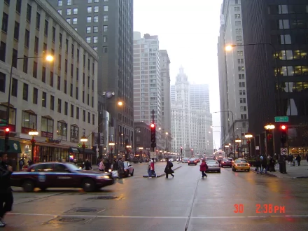 HD PC desktop wallpaper showcasing a bustling man-made Chicago street scene with traffic and pedestrians between tall city buildings at dusk.