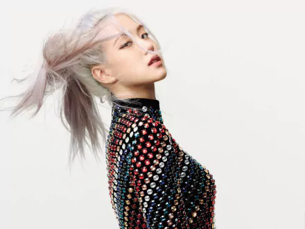 Rosé from BlackPink poses with flowing hair and a studded outfit in a high-resolution 4K Ultra HD K-pop music wallpaper.