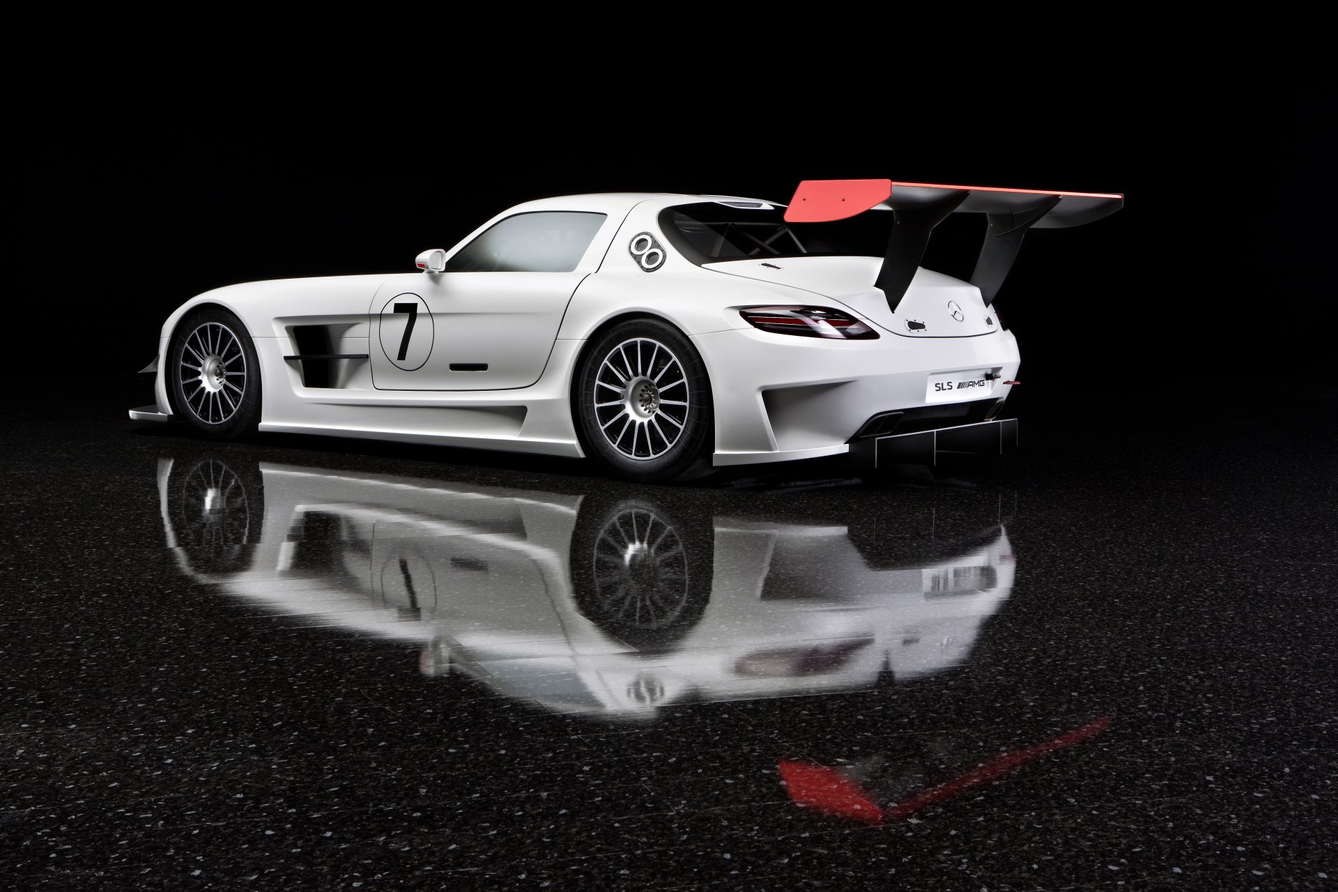 A white Mercedes-Benz SLS AMG sports car with a large rear wing, showcased on a reflective black surface in 4K Ultra HD resolution.