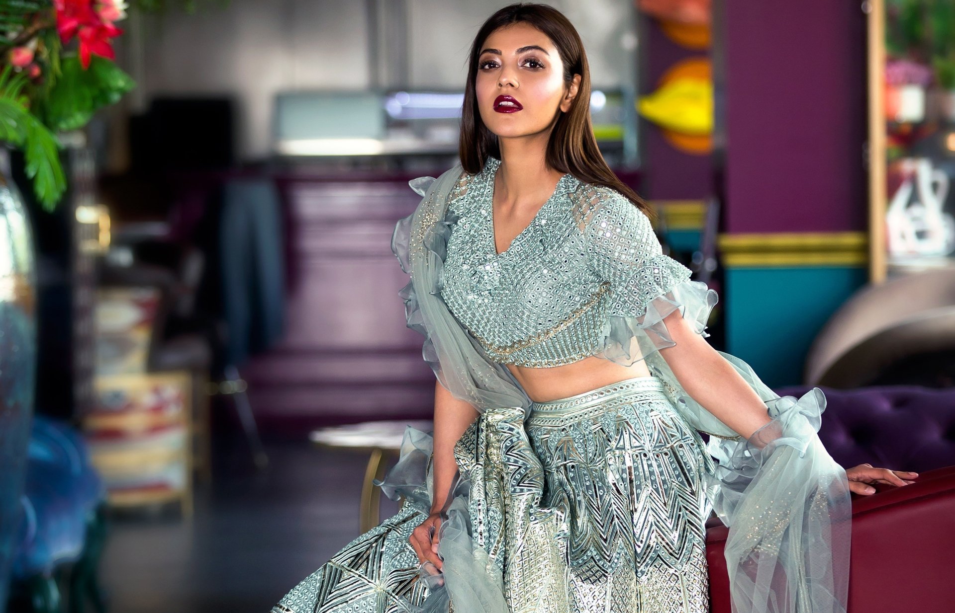 Woman in ornate mint-green lehenga striking a pose in a colorful indoor lounge; 2K Quad HD PC desktop wallpaper.