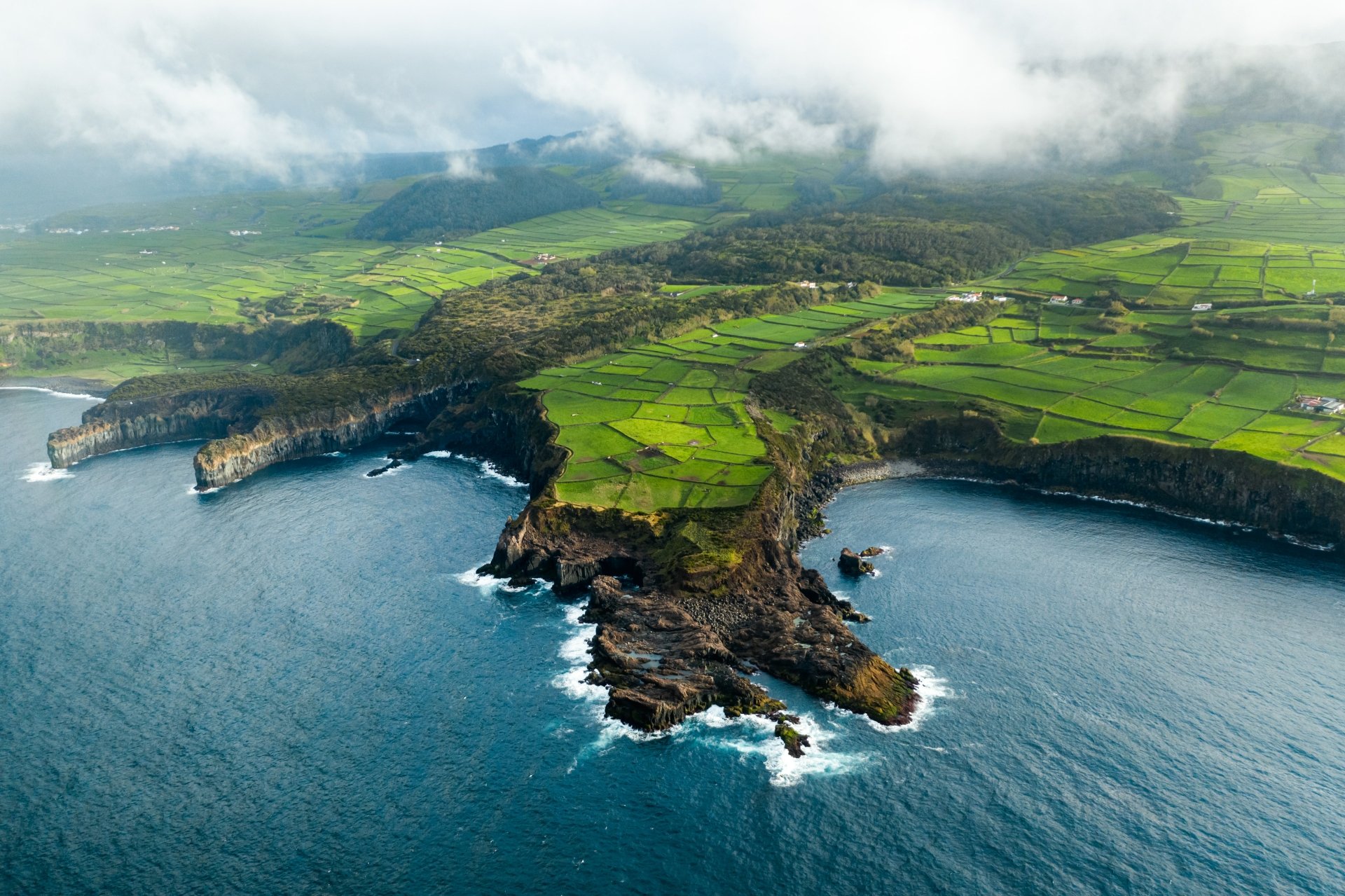 Aerial view of a rugged coastline with cliffs and patchwork green fields under low clouds — 4K Ultra HD PC desktop wallpaper and background, nature coastline.