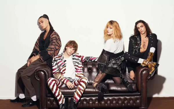 Band members posing stylishly on a brown leather couch with a white backdrop for a HD Maneskin desktop wallpaper.