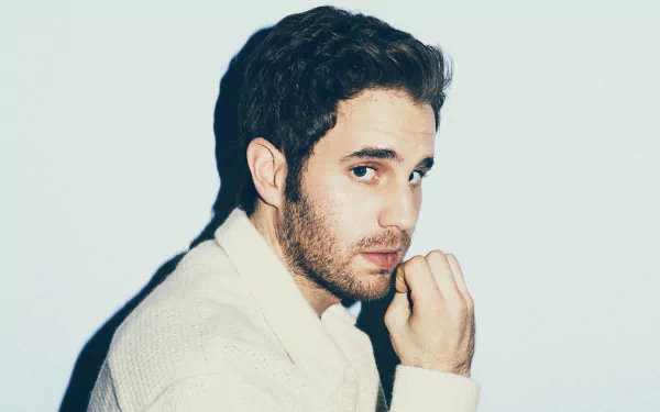 Man in a white sweater posing thoughtfully for a HD desktop wallpaper.