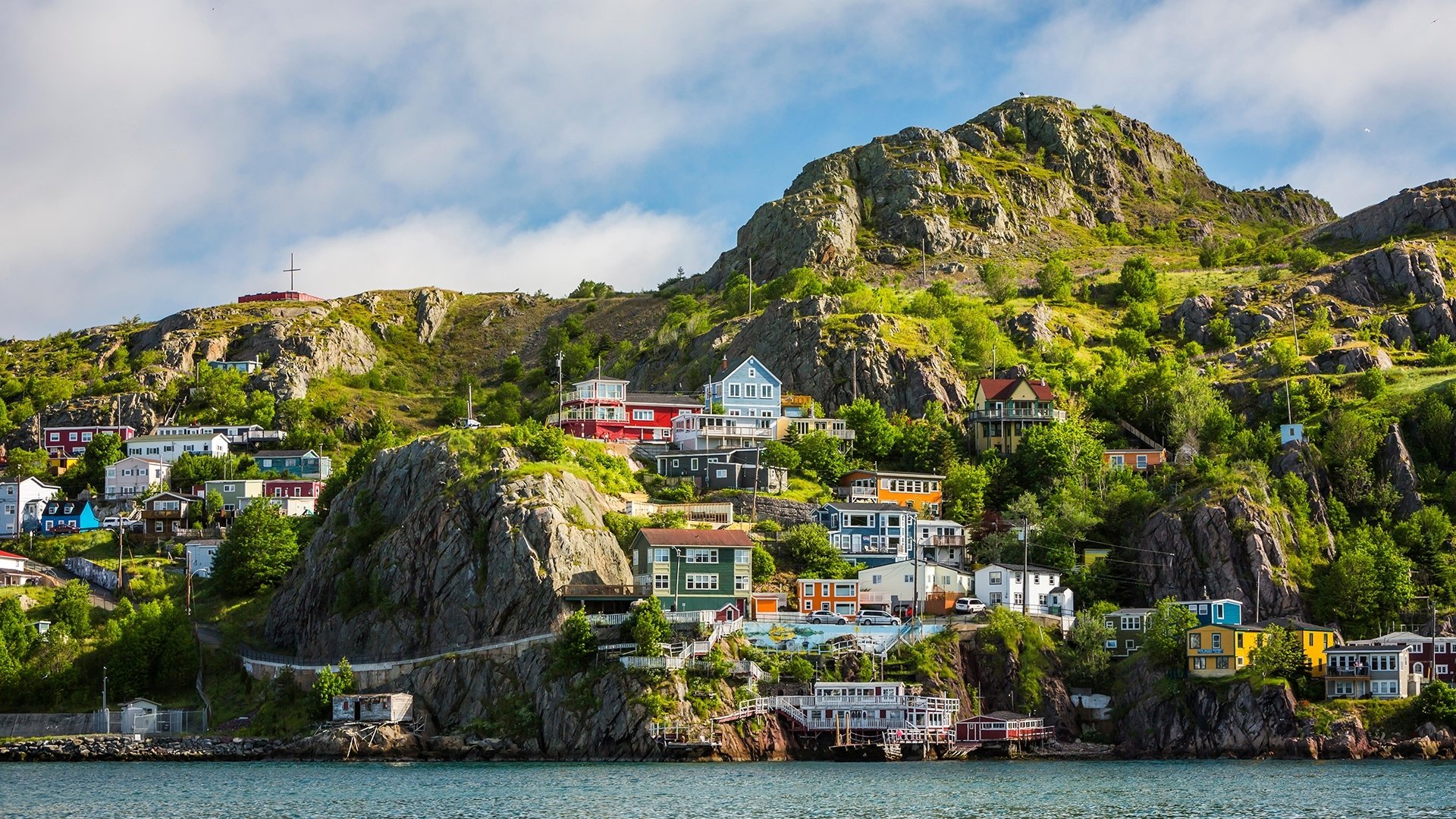 HD PC desktop wallpaper/background: a coastal village of colorful man-made houses built on rocky hillsides above the water beneath a blue sky.