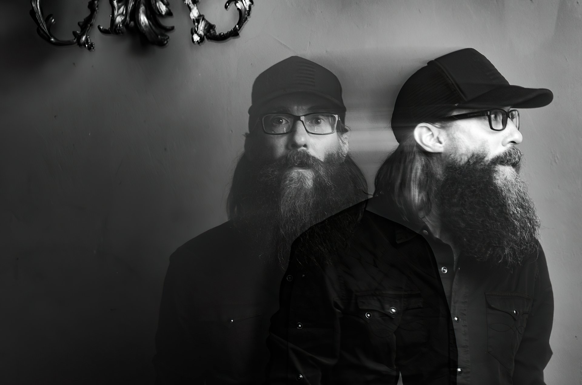 Monochromatic HD desktop wallpaper featuring a double exposure portrait of a bearded person in a cap, tagged with Crowder, with a subtle antler fixture in the background.
