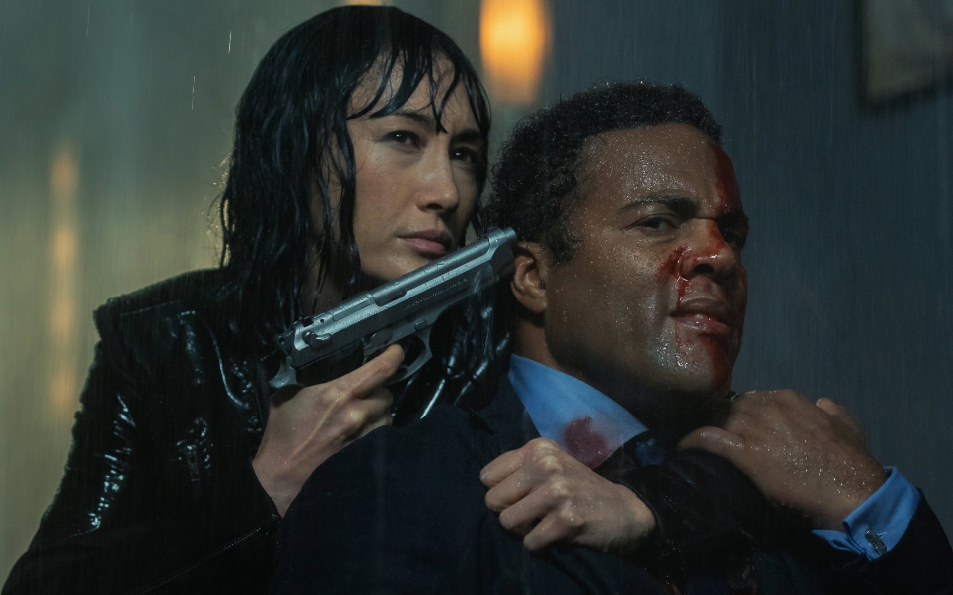 HD desktop wallpaper featuring actors Ray Fearon and Maggie Q in a tense scene from the movie The Protégé, with Maggie Q holding a gun to Ray Fearon's head.