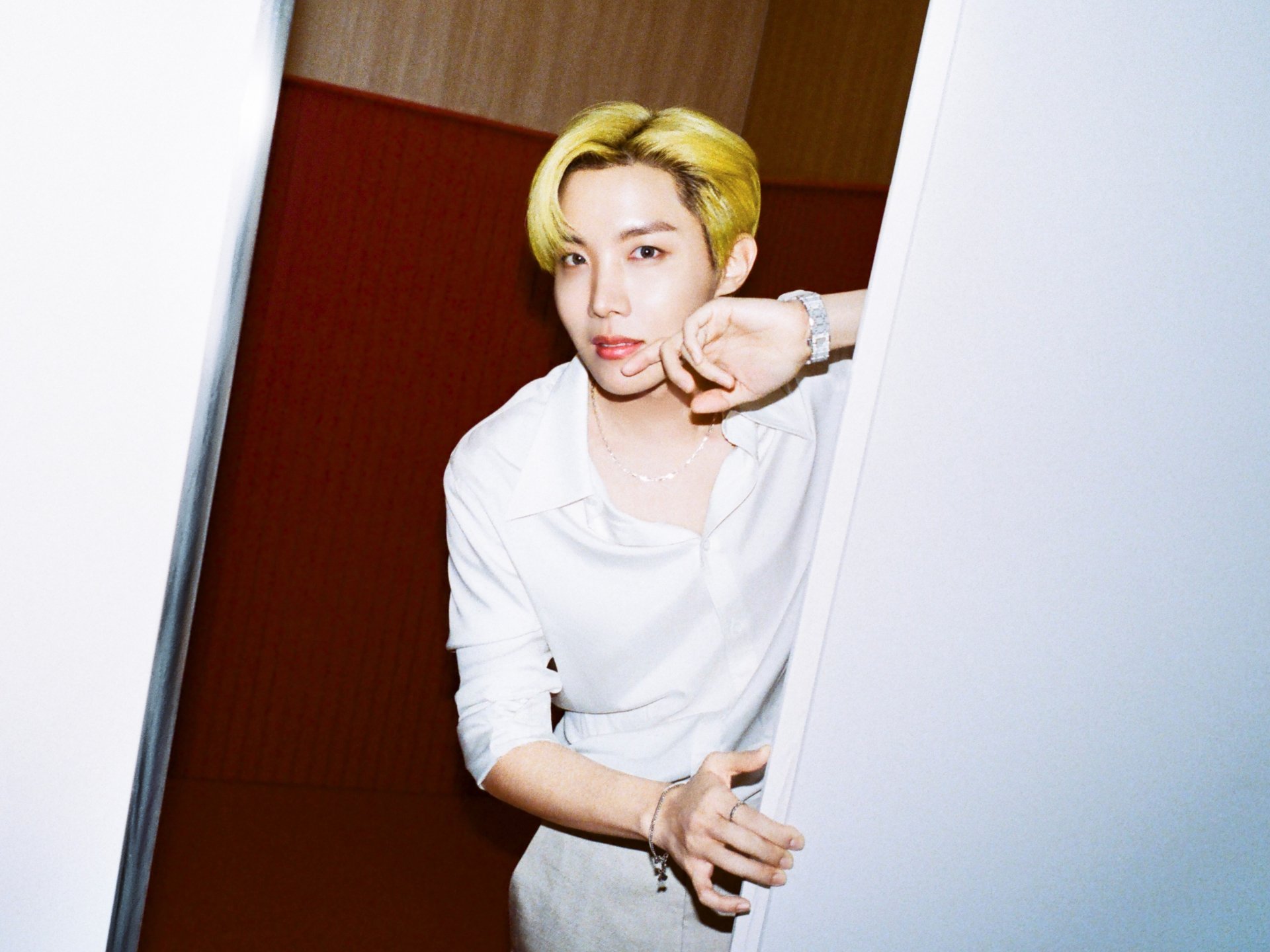 HD PC desktop wallpaper of a K-pop singer with blond hair in a white shirt, leaning from a doorway; minimalist music-themed background and crisp portrait-style composition.