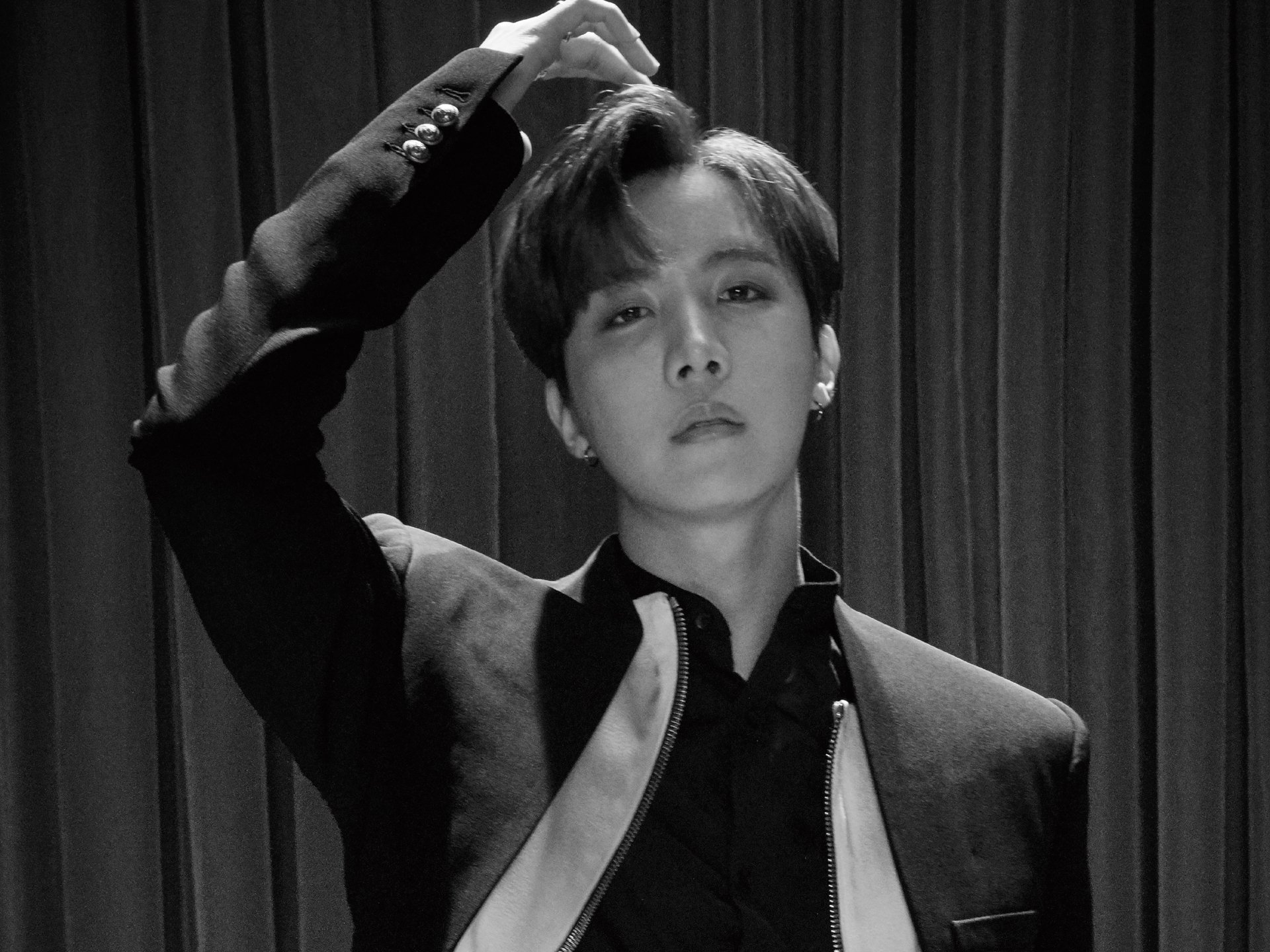 Black and white HD wallpaper of J-Hope from BTS, captured in a stylish pose, reflecting the dynamic energy of K-pop music and the artist's charisma.