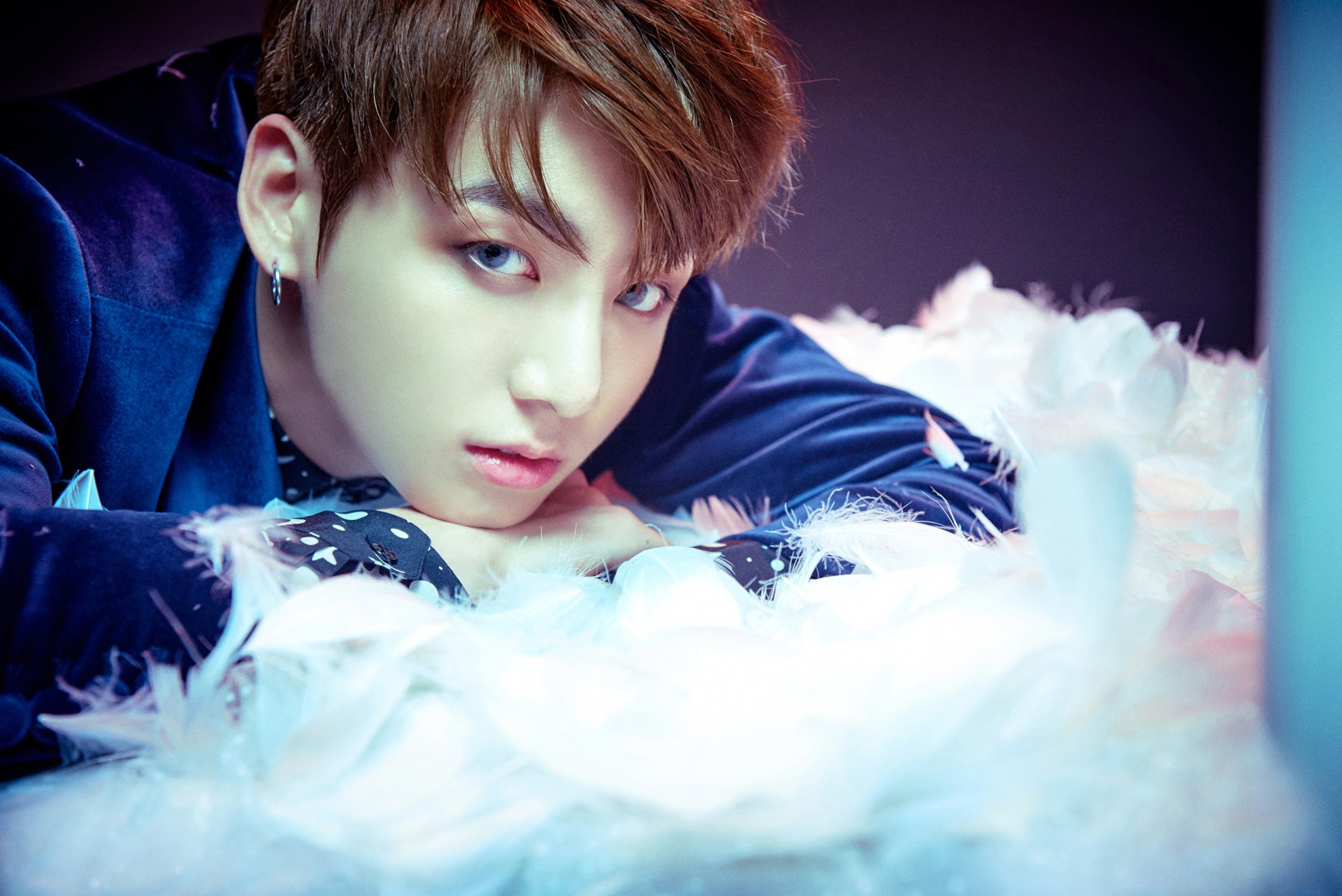 HD PC wallpaper featuring Jungkook, the K-pop singer from BTS, surrounded by soft white feathers with a dreamy, colorful background.