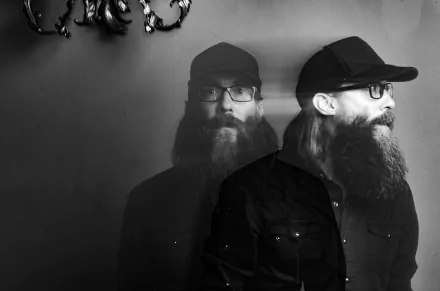 Monochromatic HD desktop wallpaper featuring a double exposure portrait of a bearded person in a cap, tagged with Crowder, with a subtle antler fixture in the background.