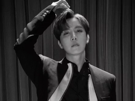 Black and white HD wallpaper of J-Hope from BTS, captured in a stylish pose, reflecting the dynamic energy of K-pop music and the artist's charisma.
