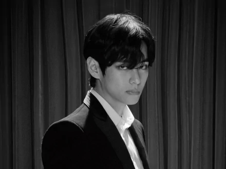 Black and white HD wallpaper of V (Kim Taehyung) from BTS, featuring the K-pop singer in a suit against a curtain backdrop.