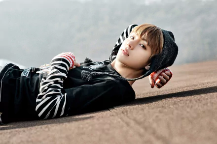 HD desktop wallpaper featuring V (Kim Taehyung) of BTS, a K-pop singer, lying down in a stylish outfit with a calm, contemplative expression.