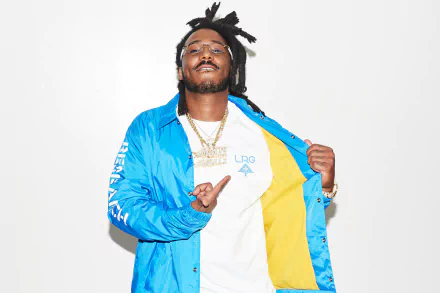 HD desktop wallpaper featuring a smiling person in a blue and yellow jacket against a white background, tagged with Mozzy.