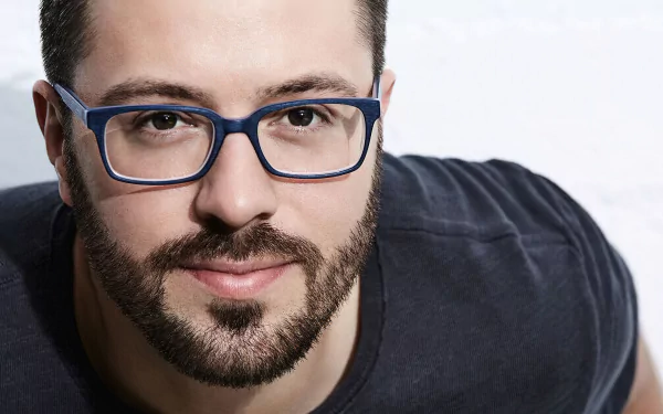 Man with glasses smiling in an HD desktop wallpaper.