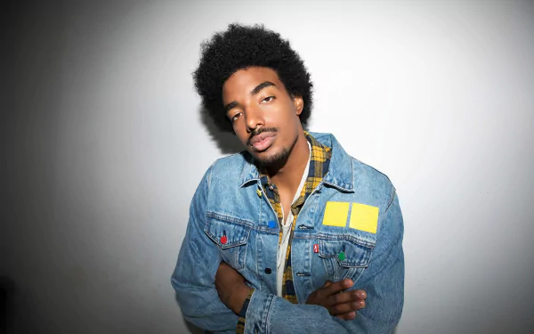 Stylish individual in a denim jacket posing with a confident smile for an HD desktop wallpaper and background.