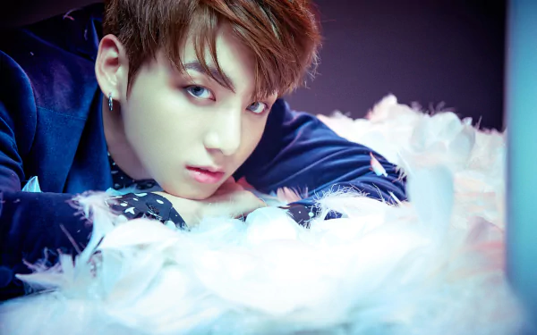 HD PC wallpaper featuring Jungkook, the K-pop singer from BTS, surrounded by soft white feathers with a dreamy, colorful background.