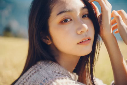 Close-up portrait of a young woman bathed in soft sunlight, 4K Ultra HD PC desktop wallpaper with a softly blurred outdoor field background.