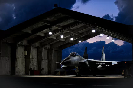 McDonnell Douglas F-15 Eagle jet fighter warplane sits in a dimly lit hangar under a cloudy evening sky, captured in stunning 8K Ultra HD detail.