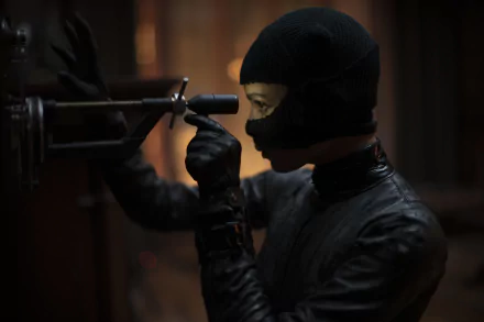A masked character in black tactical gear manipulates a device in a dark setting, featured in an 8K Ultra HD PC desktop wallpaper from the movie The Batman.