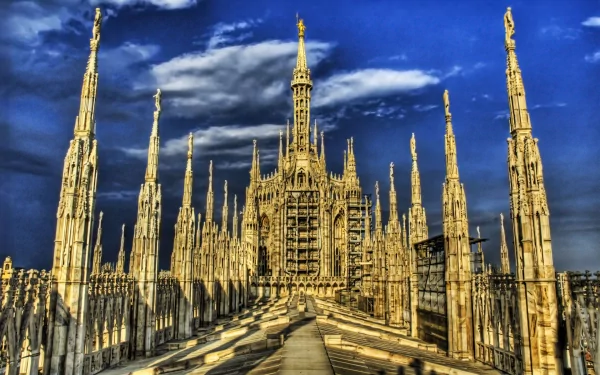 A stunning HD wallpaper showcasing the intricate architecture of the Milan Cathedral, featuring its towering spires against a vibrant blue sky, reflecting its historical and religious significance.