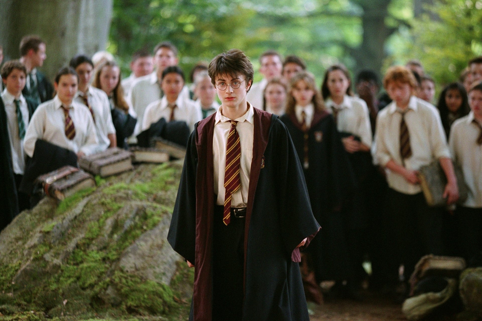 Young wizard in Hogwarts robes stands before classmates in a wooded clearing — scene from the movie Harry Potter and the Prisoner of Azkaban, 2K Quad HD PC desktop wallpaper.