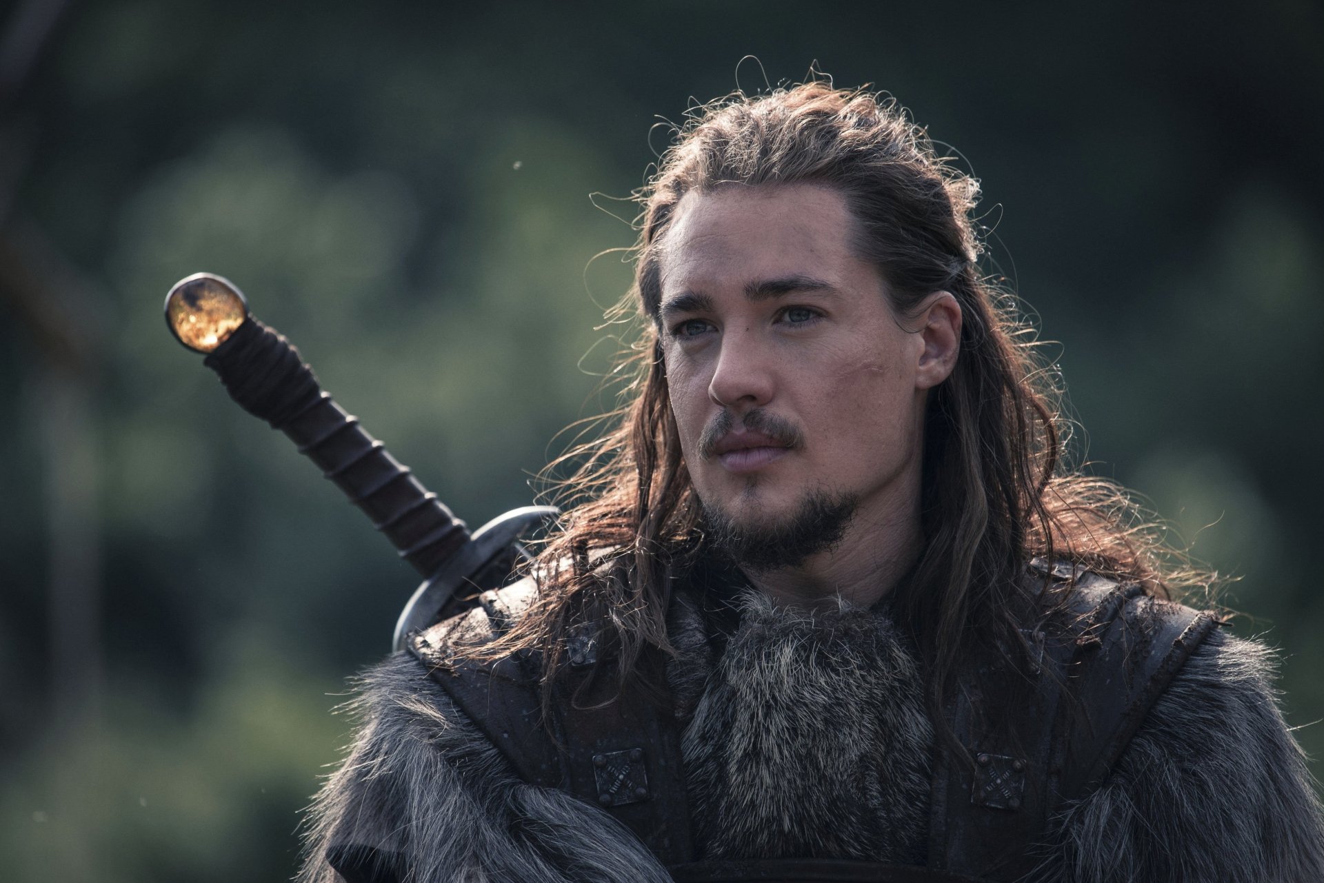 4K Ultra HD PC desktop wallpaper: fur-clad warrior from the TV show The Last Kingdom, long hair and beard, sword on his back against a misty forest backdrop.