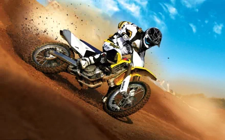A dynamic HD desktop wallpaper of a Suzuki dirt bike speeding through a dusty terrain under a bright blue sky.