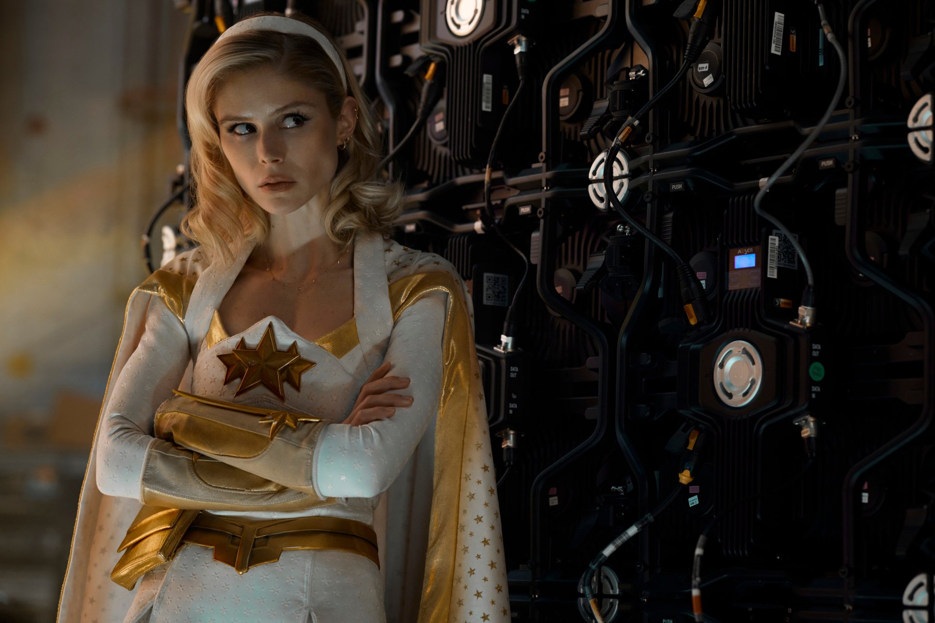 Starlight from TV show The Boys (2019) in white-and-gold hero costume, arms crossed against a dark wall of cables and equipment — 2K Quad HD PC desktop wallpaper/background