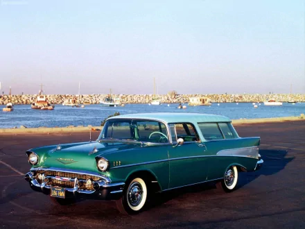 HD desktop wallpaper featuring a classic green Chevrolet Nomad parked by a waterfront with boats in the background under a clear sky.