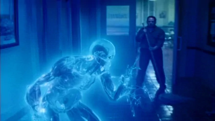 A dramatic scene from the movie *Watchmen*, featuring Doctor Manhattan, a luminous blue figure, against a dark background with a standing man in the foreground. HD wallpaper.
