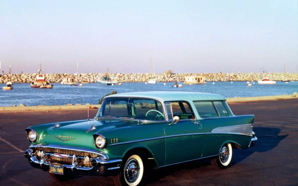 HD desktop wallpaper featuring a classic green Chevrolet Nomad parked by a waterfront with boats in the background under a clear sky.