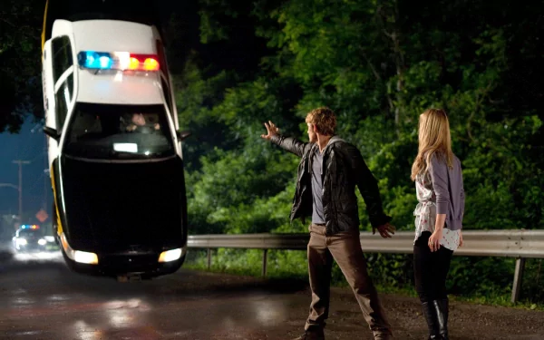 A scene from the movie *I Am Number Four*, featuring a character using telekinesis to levitate a police car, while another character watches, set against a nighttime forest backdrop.