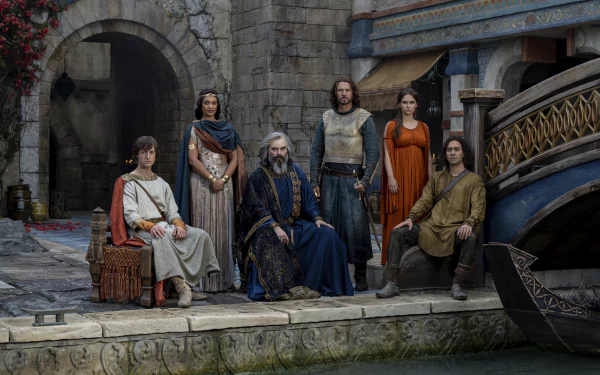4K Ultra HD PC desktop wallpaper: group of robed characters from TV show The Lord of the Rings: The Rings of Power posed on a stone waterfront set.
